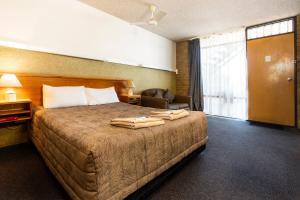 a hotel room with a bed with towels on it at Town Centre Motor Inn in Merimbula