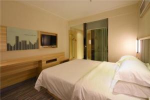 a bedroom with a white bed and a tv at City Comfort Inn Changsha Window of the World Zhongmao City in Xingsha