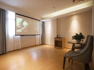 Una gran pantalla en una habitación con una silla y una mesa en GreenTree Inn Shangrao Wuyishan Avenue Meide Yinxiang, en Shangrao