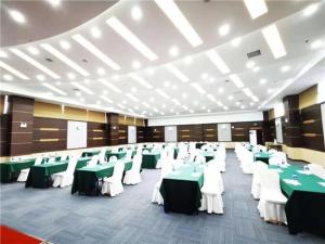 um salão de banquetes com mesas e cadeiras verdes e brancas em E-Cheng Hotel Dali High-Speed Railway Station Erhai Lake em Dali