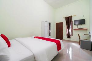 a bedroom with two white beds and a television at RedDoorz Syariah Near RSUD Dr HM Rabain in Muaraenim