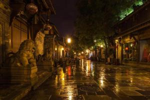 uma rua da cidade molhada à noite com uma chuva em Borrman Hotel Chengdu Chunxi Road Tianfu Square Metro Station em Chengdu