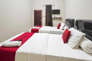 two beds in a room with red and white at RedDoorz Syariah Near RSUD Dr HM Rabain in Muaraenim