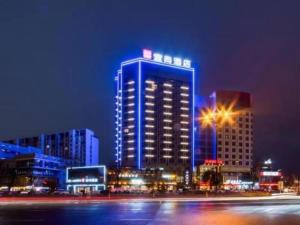 un gran edificio con luces azules por la noche en Echarm Hotel Huzhou Wuyue Plaza Children's Clothing City en Jijiawan