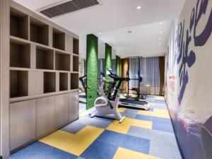 a fitness room with a gym with a treadmill at Echarm Hotel Huzhou Wuyue Plaza Children's Clothing City in Jijiawan
