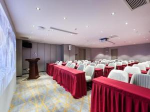 una sala de conferencias con mesas y sillas rojas y un podio en Echarm Hotel Huzhou Wuyue Plaza Children's Clothing City en Jijiawan