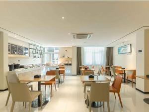 BengbuにあるCity Comfort Inn Bengbu Jiefang Road Wuyue Plazaのテーブルと椅子のあるレストラン、キッチンが備わります。