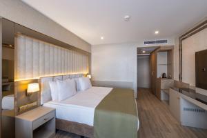 Belenli Resort Hotel في بيليك: غرفه فندقيه سرير كبير وتلفزيون