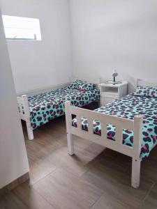 a bedroom with two beds and a bench in it at Alewyn, our little happy house on a hill in Stilbaai