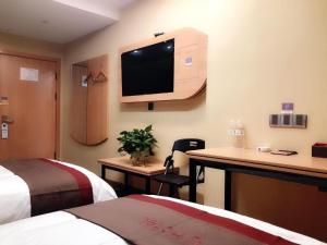 a hotel room with two beds and a tv on the wall at Thank Inn Hotel Inner Mongolia Baotou Donghe Haode Trade Plaza in Baotou