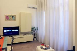 soggiorno con TV e tende bianche di Dimora San Fermo 11 a Verona