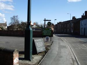 una calle vacía con una señal junto a un poste en The Downe Arms en Snaith