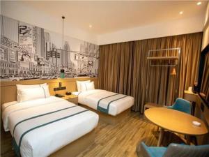 City Comfort Inn Yangzhou Jiangdu North Limin Road في Jiangdu: غرفة فندقية بسريرين وطاولة