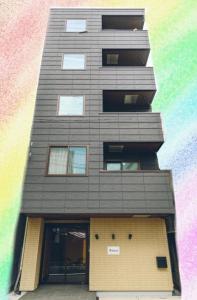 un edificio alto con un arco iris delante de él en winco, en Tokio