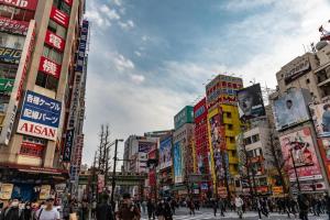 una multitud de personas caminando en una ciudad con edificios en winco, en Tokio