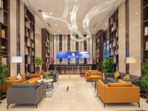 un vestíbulo con sofás y mesas en un edificio en VX Hotel Wuxi Xinwu District Executive Center Wanda Plaza en Xin'an