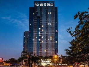 un edificio alto con un cartel en el costado en VX Hotel Wuxi Xinwu District Executive Center Wanda Plaza en Xin'an
