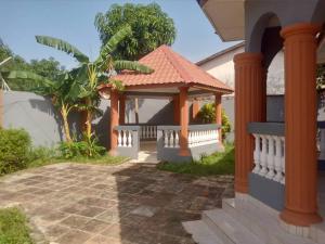 a house with a gazebo and a palm tree at Costal Road Hideout in Serekunda