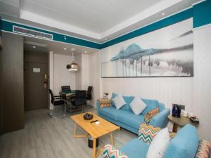 uma sala de estar com um sofá azul e uma mesa em VX Hotel Shangrao High-Speed Railway Station em Shangrao