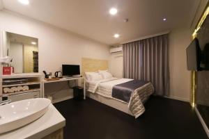 um quarto de hotel com uma cama e um lavatório em Prince Motel em Busan