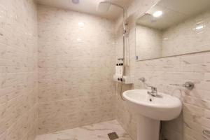 a white bathroom with a sink and a mirror at Prince Motel in Busan