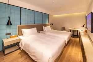 a hotel room with two beds and a table at Ji Hotel Xiamen Railway Station North Square in Jiangtouzhen