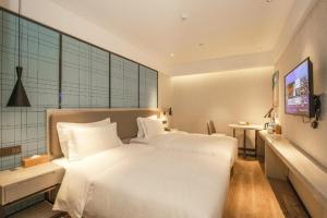 a bedroom with a large white bed and a television at Ji Hotel Xiamen Railway Station North Square in Jiangtouzhen