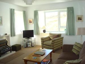 a living room with a couch and a tv at Harris White Cottage in Rodel