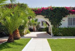 a garden with a palm tree and an arch with flowers at Beautiful Villa La Caracola in Marbella