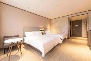 a hotel room with two beds and a table at Hanting Hotel Suqian Powerlong Plaza in Suqian