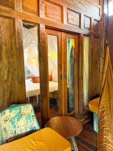 um quarto com paredes de madeira, uma cama e uma cadeira em Blue Earth Village em Amed