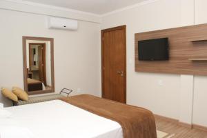 a bedroom with a bed and a tv on a wall at Hotel Areias Brancas in Rosário do Sul