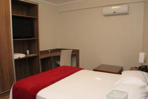 a hotel room with a bed with a red blanket on it at Hotel Areias Brancas in Rosário do Sul