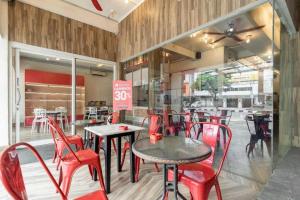 un restaurant avec des chaises rouges, des tables et des fenêtres dans l'établissement RedDoorz Plus @ Jalan Veteran Palembang, à Palembang