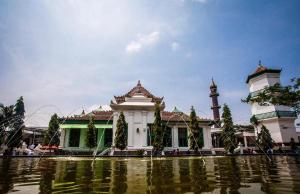 un grand bâtiment blanc avec une tour d'horloge à côté d'une masse d'eau dans l'établissement RedDoorz Plus @ Jalan Veteran Palembang, à Palembang