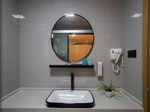 a bathroom with a sink and a mirror at Shell Hotel Wuxi Gonghu Avenue Vientiane City in Zhongqiao