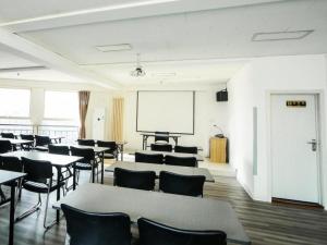 una habitación de clase con mesas, sillas y una pantalla en GreenTree Alliance Hotel Qinghuangdao Wanda Plaza en Qianmafang