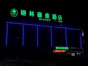a building with a blue and green sign at night at Green Tree Inn Lianyungang Guannan County Duigougang Town in Chaohe