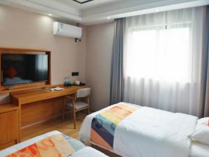 Habitación de hotel con 2 camas y escritorio con TV. en Shell Hotel Wuhu Jiujiang District Daqiao Town Huashan Road en Wanli