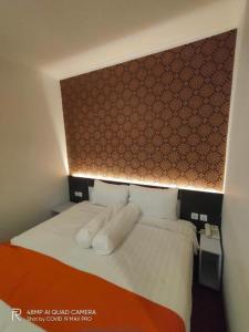 a bedroom with a bed with white sheets and pillows at Front One Boutique Tugu Muda Semarang in Semarang