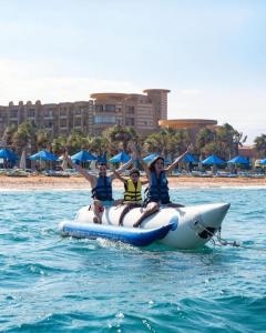 three people are riding on a raft in the water at Grand Ocean Sokhna Hotel in Ain Sokhna
