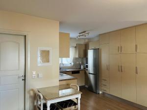 a kitchen with a table and a stainless steel refrigerator at Vasilias Home near Ath Airport in Koropi