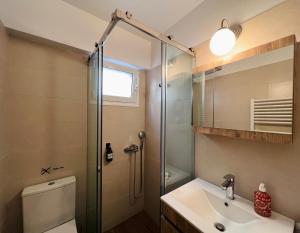 y baño con ducha, aseo y lavamanos. en Vasilias Home near Ath Airport, en Koropíon