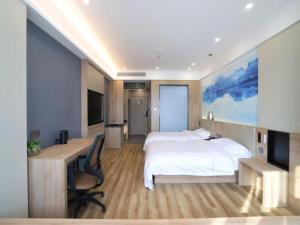 a bedroom with a large white bed and a desk and a computer at VX Hotel Jiangsu Taizhou Xinghua RT-Mart in Xinghua