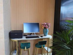 a computer on a desk with two chairs and a vase of flowers at GreenTree Inn Luoyang Railway Station Wangfujing Wangcheng Park in Luoyang