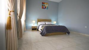 ein Schlafzimmer mit einem Bett und zwei Lampen auf einem Fliesenboden in der Unterkunft Kris Apartment in Ibadan
