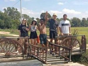 un grupo de personas de pie en un puente de madera en Meta Homestay en Phumĭ Puŏk Chăs