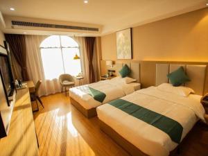 ein Hotelzimmer mit 2 Betten und einem TV in der Unterkunft GreenTree Inn Jumang Plaza in Mangshi