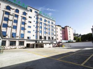 Mangshi的住宿－GreenTree Inn Jumang Plaza，一座大型建筑,前面设有停车场