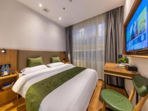 a bedroom with a large bed and a flat screen tv at GreenTree Inn Express Lanzhou West Passenger Station Lanzhou Center in Lanzhou